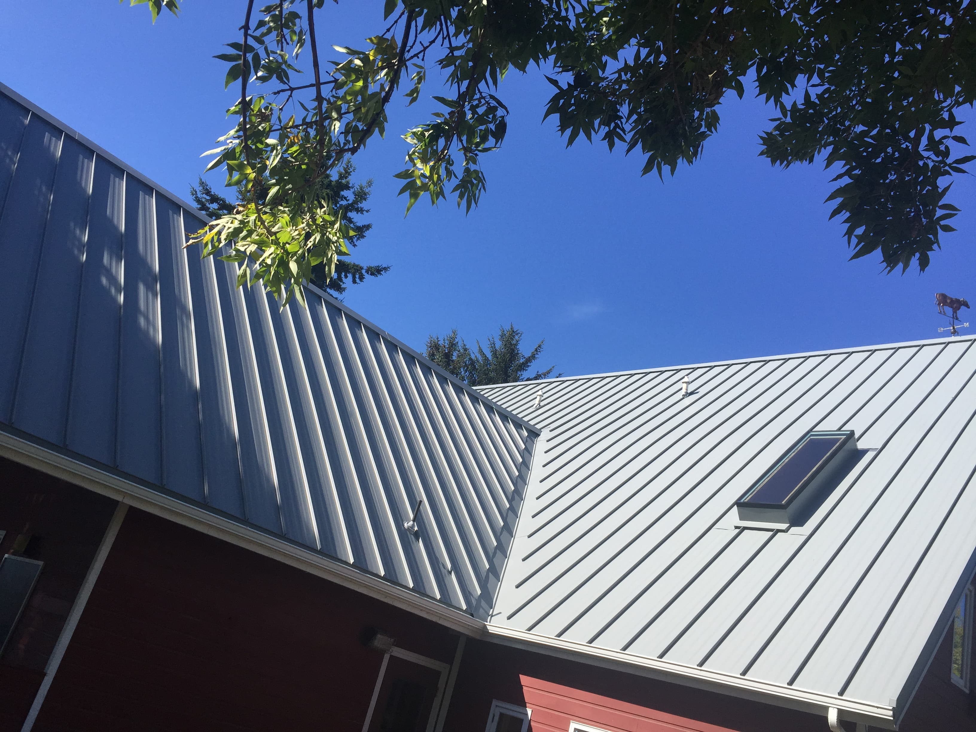Gray standing seam metal roof with a skylight under a clear blue sky