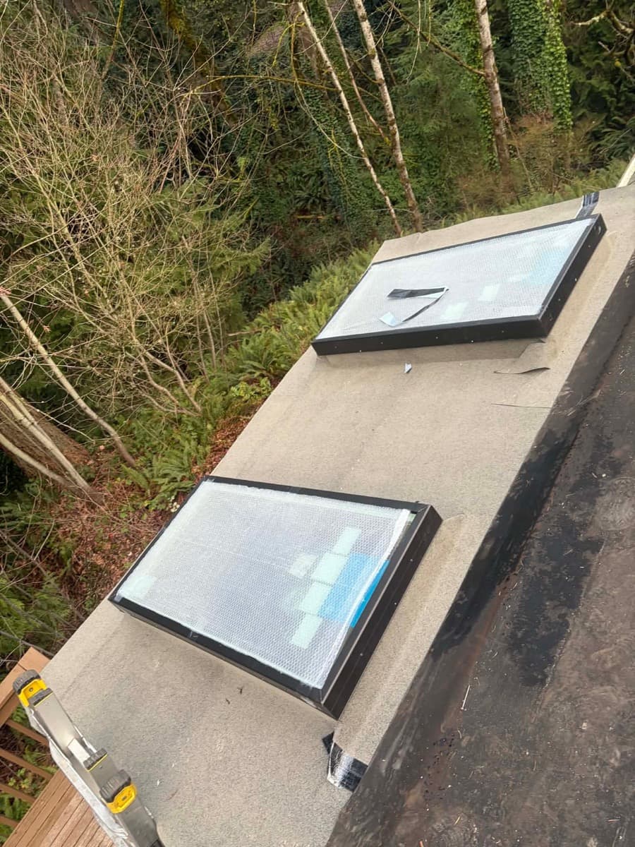 Flat membrane roof section with two skylights, seen from above