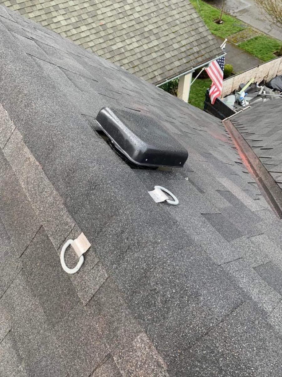 Roof vent and a tie-off anchor on a dark shingle slope