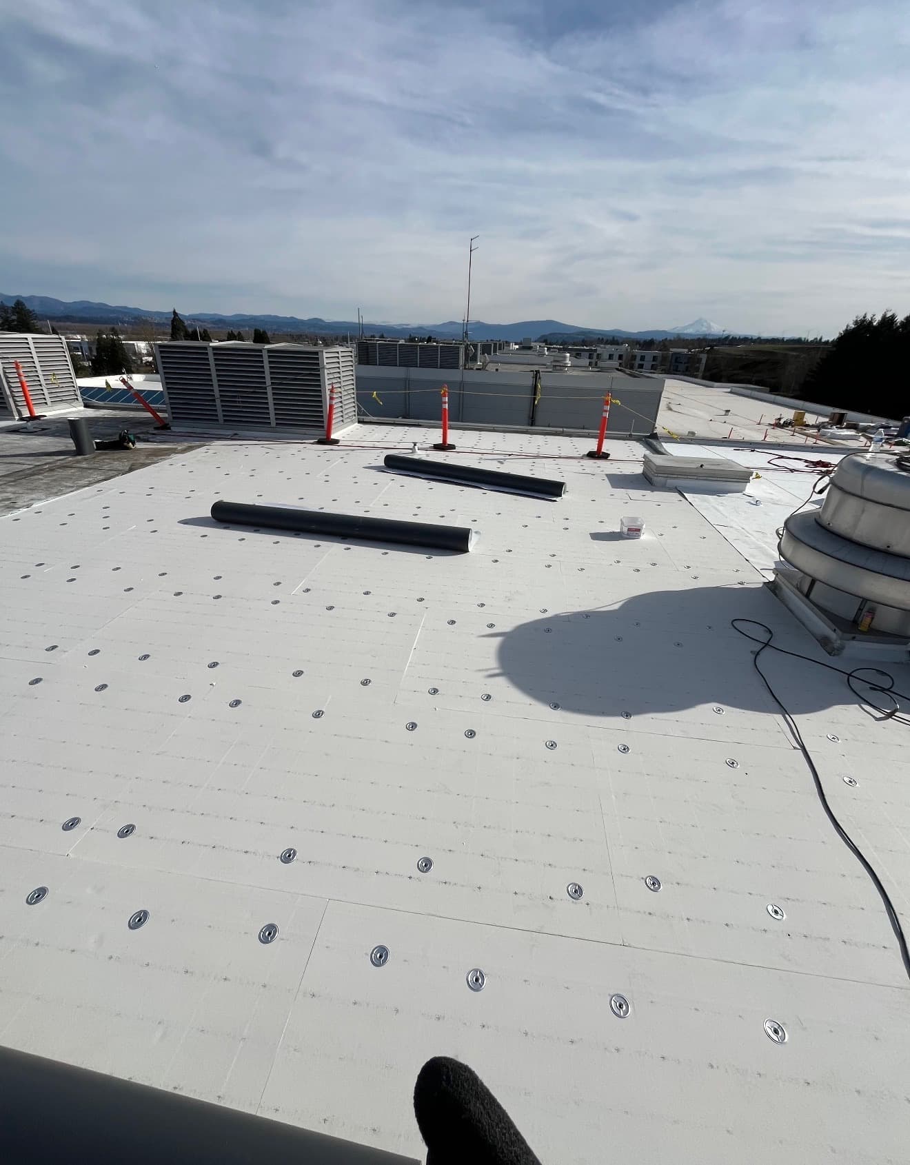 Large white flat roof with rooftop equipment and distant hills
