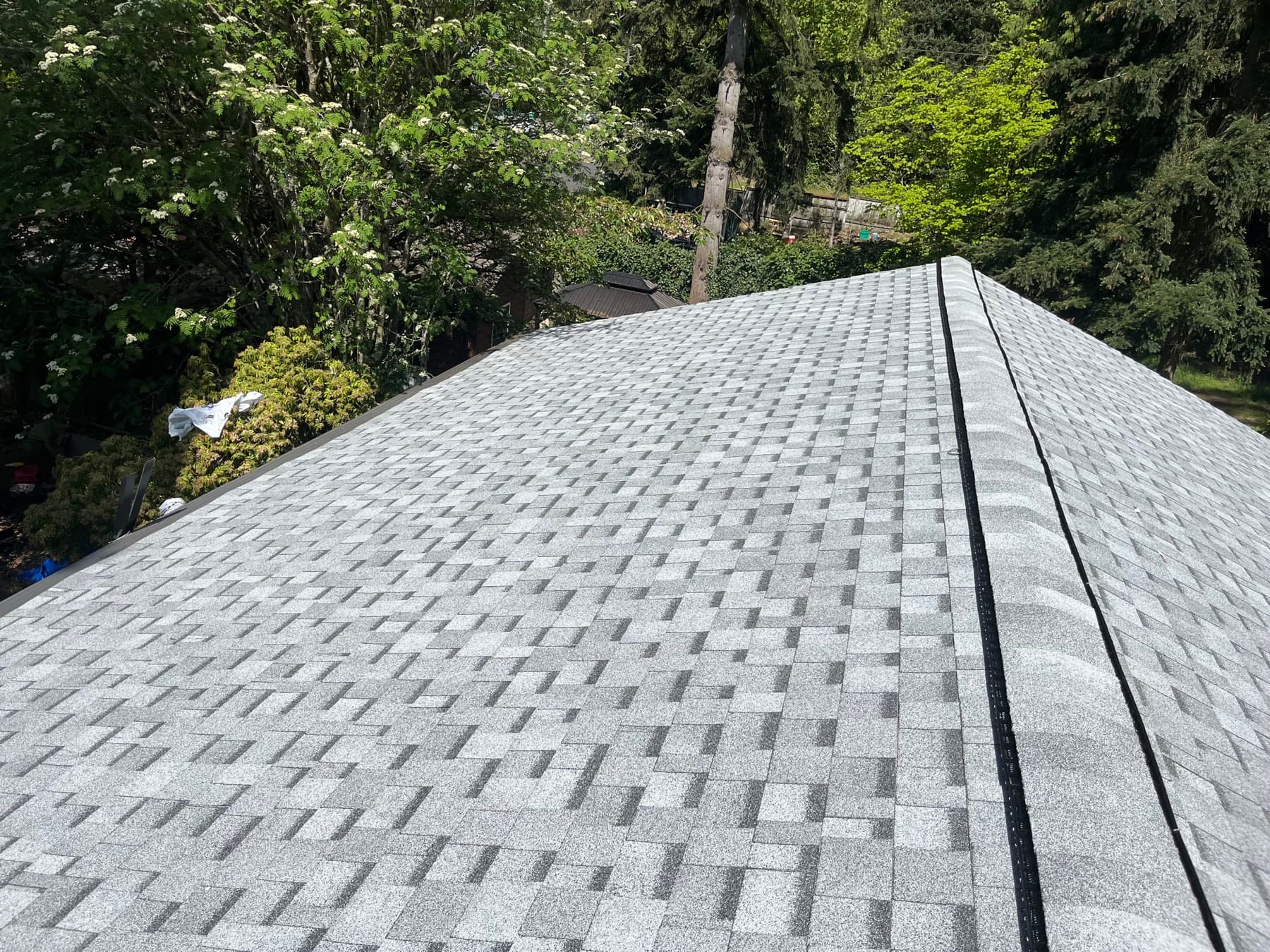 New asphalt shingles laid in even courses up to a capped hip ridge